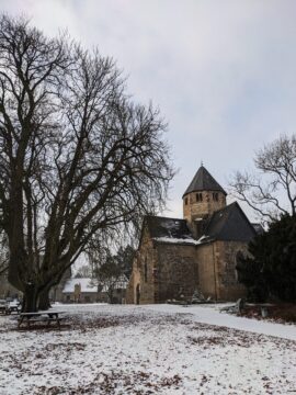 Im Hintergrund ein historisches Gebäude, ein Baum ohne Laub. Es liegt Schnee.